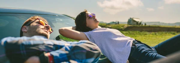 Young couple lying on the windshield — Stock Photo, Image
