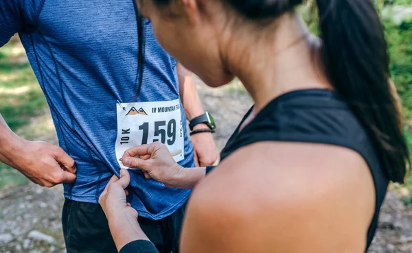 Trail atleta colocando el número de carrera a su pareja — Foto de Stock