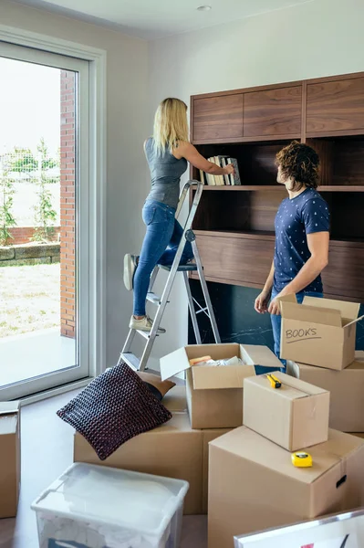 Par uppackning lådor och att placera böcker — Stockfoto