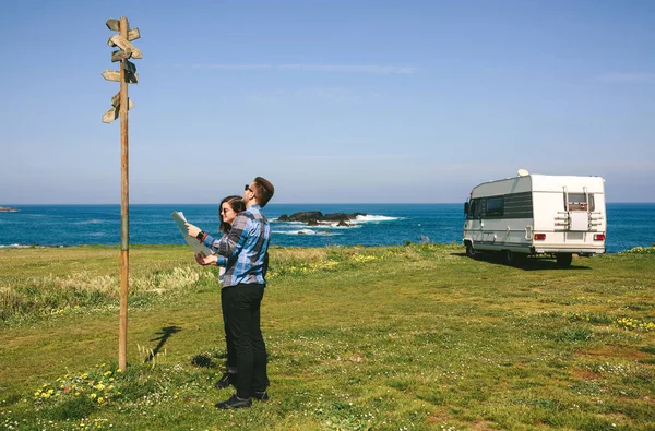 Casal jovem procurando um mapa e sinal de direção — Fotografia de Stock