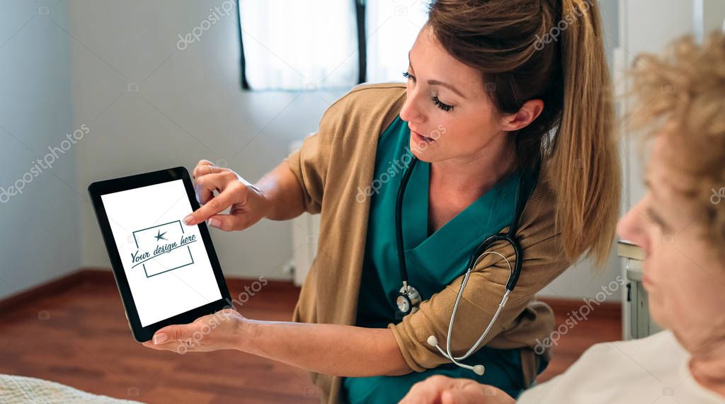 Female doctor showing tablet to female senior patient. Customizable tablet screen