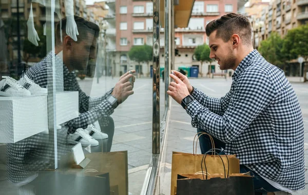 Homem tirando uma foto de uma vitrine de uma loja de moda — Fotografia de Stock