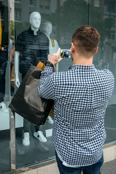 Мужчина фотографирует витрину магазина моды — стоковое фото