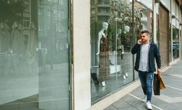Man with shopping bags in front clothing store — Stock Photo, Image