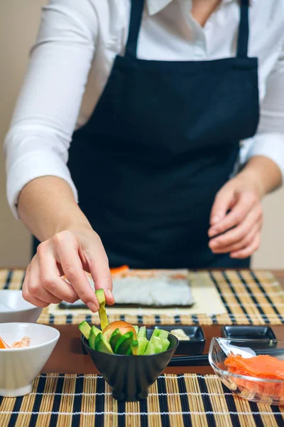 Chef-kok oppakken van gesneden avocado te maken sushi — Stockfoto