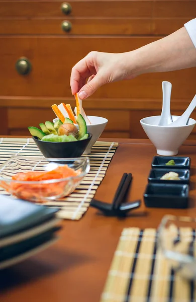 Main de chef ramassant un bâton de crabe pour faire des sushis — Photo