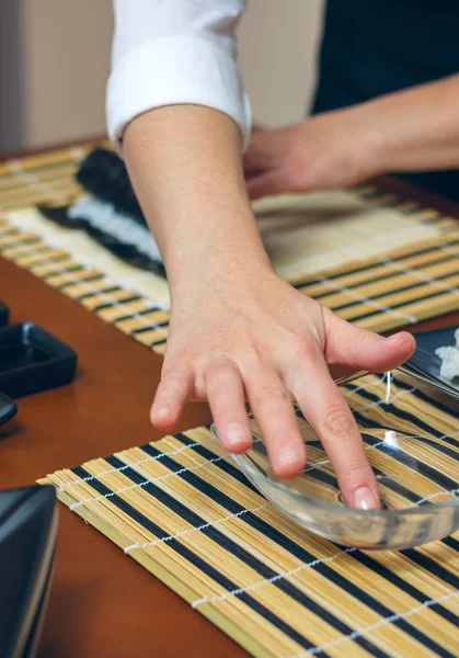 Cozinheiro feminino preparando sushi molhando a mão — Fotografia de Stock