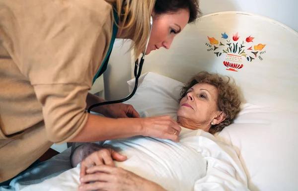 Cuidador auscultando mulher idosa — Fotografia de Stock