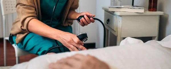 Verzorger controleren bloeddruk tot een senior vrouw — Stockfoto