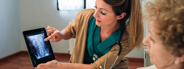 Γυναίκα γιατρό δείχνει μια ακτινογραφία στο tablet — Φωτογραφία Αρχείου