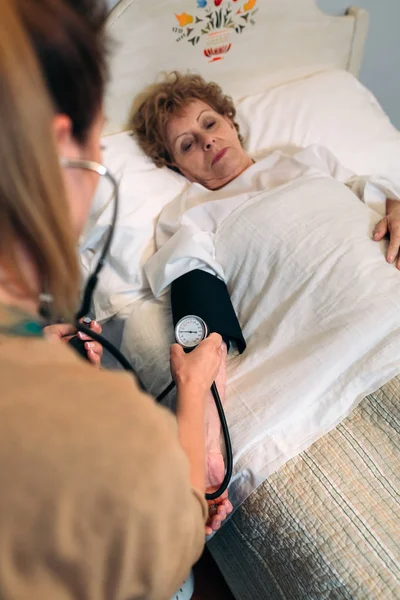 Cuidador revisando la presión arterial de una mujer mayor — Foto de Stock