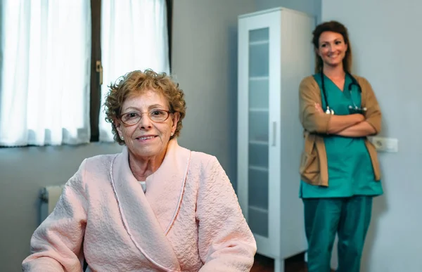Paciente de edad avanzada posando con el médico en el fondo — Foto de Stock