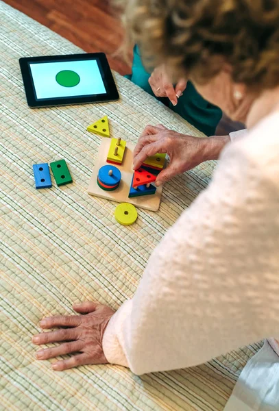 Female doctor showing geometric shapes to elderly patient — Stock Photo, Image