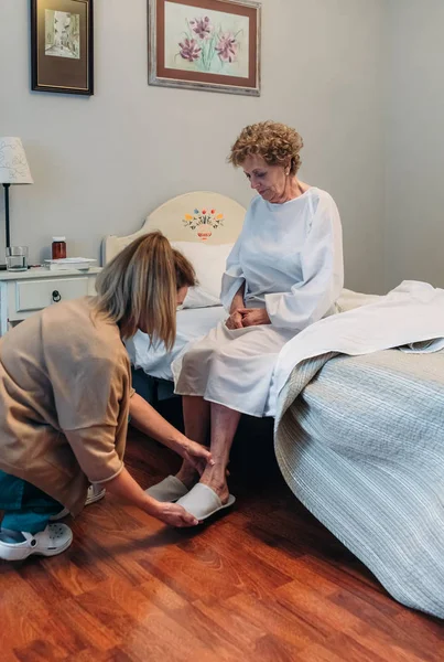 Cuidador que usa zapatillas para pacientes ancianos — Foto de Stock