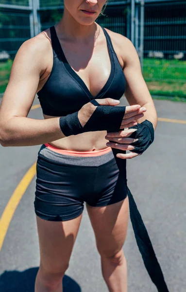 Idrottskvinna sätta på boxning bandage — Stockfoto