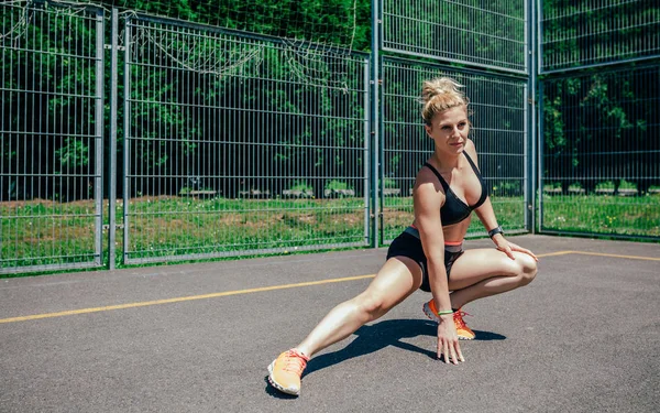 Sportswoman doing leg stretches — Stock Photo, Image