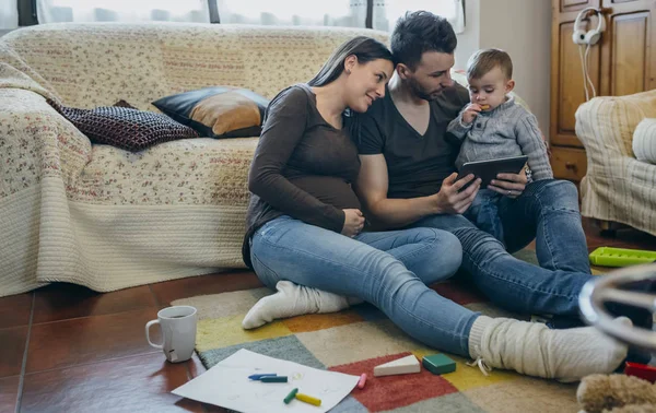 Famiglia con bambino e madre incinta alla ricerca di tablet — Foto Stock