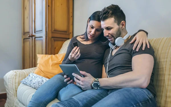 Беременная с партнером смотрит на планшет — стоковое фото
