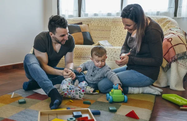 Padres con su pequeño hijo abriendo un regalo —  Fotos de Stock