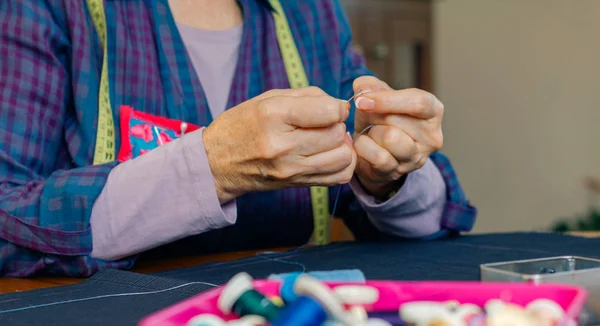 Senior vrouwelijke naaister threading een naald — Stockfoto