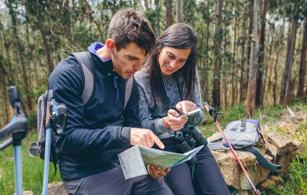 Couple faisant trekking assis à la recherche mobile et la carte — Photo