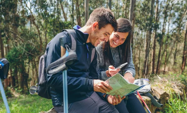 Couple doing trekking sitting looking mobile and map — Stock Photo, Image