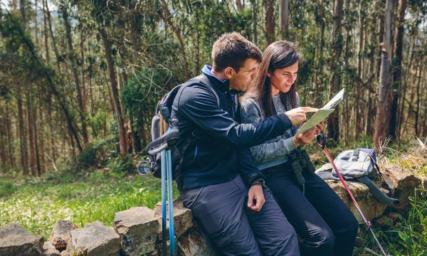 Couple doing trekking sitting looking at a map — Stock Photo, Image