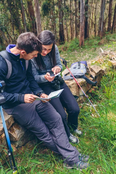 Couple doing trekking sitting looking mobile and map — Stock Photo, Image