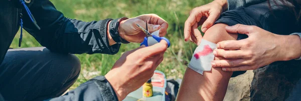 Man healing knee to woman who has been injured trekking — Stock Photo, Image