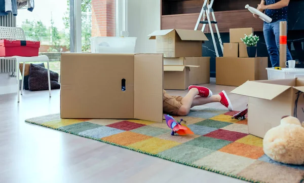 Chico jugando dentro de una caja en movimiento mientras su padre desempaca —  Fotos de Stock