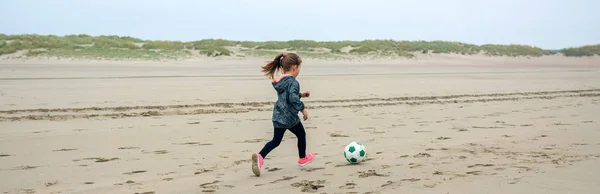 Niña jugando fútbol en la playa — Foto de Stock