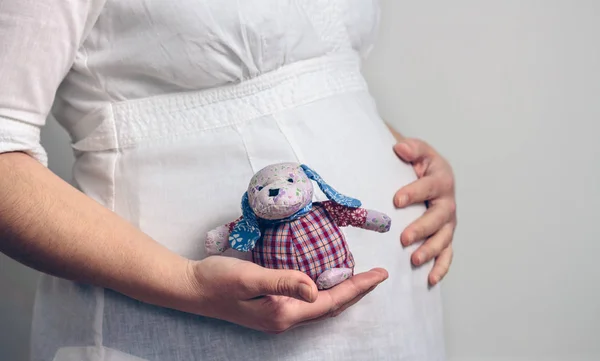 Embarazada sosteniendo una muñeca de trapo bebé — Foto de Stock