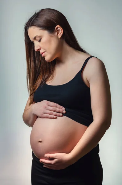 Beautiful pregnant looking her belly isolated — Stock Photo, Image