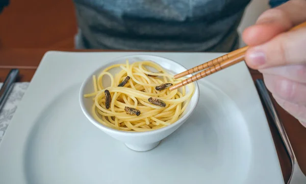 Mannen äter spagetti och syrsor — Stockfoto