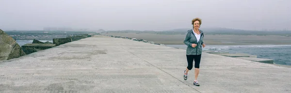 Senior sportswoman with headphones running — Stock Photo, Image