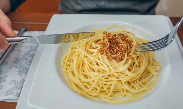 Menschenhände essen Spaghetti mit Würmern — Stockfoto