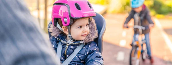 Chica Lttle con casco en la cabeza sentado en el asiento de la bicicleta —  Fotos de Stock