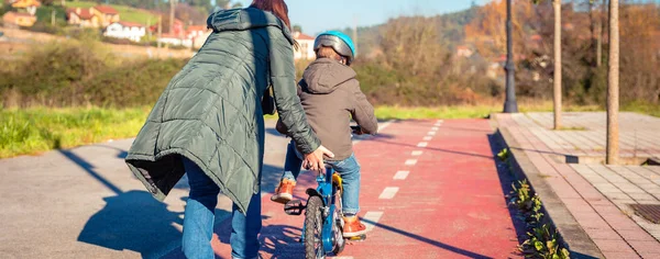 Mãe ensinando filho a andar de bicicleta na ciclovia — Fotografia de Stock
