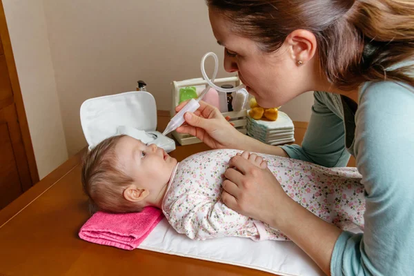 Mother using the nasal aspirator with her baby — Stock Photo, Image