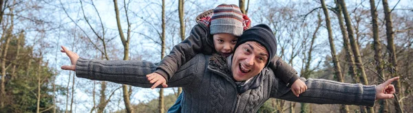 Man giving piggyback ride to happy kid in the forest — Stock Photo, Image