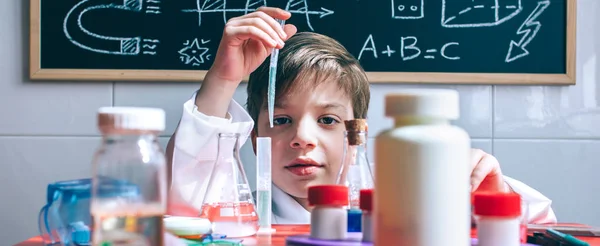 Niño jugando con líquidos químicos sobre la mesa —  Fotos de Stock