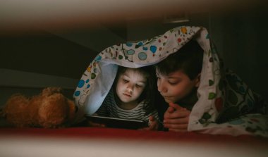 Karanlıkta tablet bakarak kardeşler