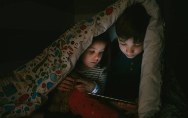 Karanlıkta tablet bakarak kardeşler