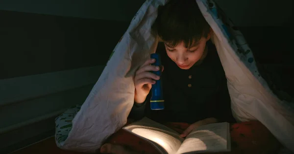 Chlapec čtení s baterkou — Stock fotografie