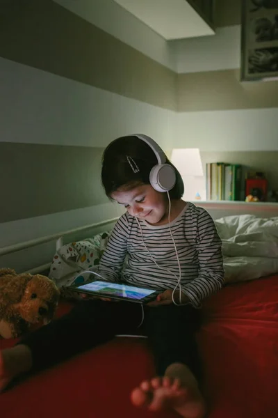 Chica con auriculares mirando a la tableta —  Fotos de Stock