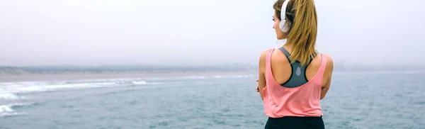 Sportswoman with headphones watching the sea — Stock Photo, Image