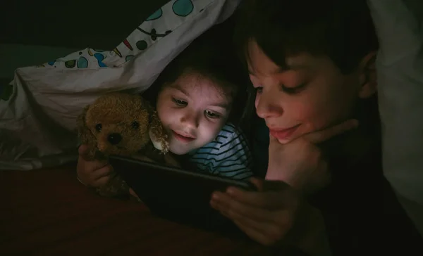 Broers kijken naar de tablet in het donker — Stockfoto