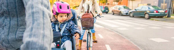 Lttle girl with helmet on head sitting in bike seat — Stock Photo, Image