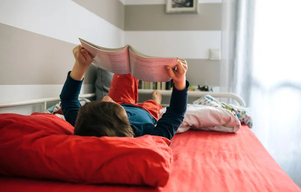 Junge liest auf seinem Bett — Stockfoto