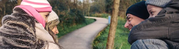 Padres dando paseo a cuestas a niños felices al aire libre — Foto de Stock